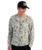 Man wearing a camouflage long-sleeve shirt with a HUK brand logo on the back, against a white background